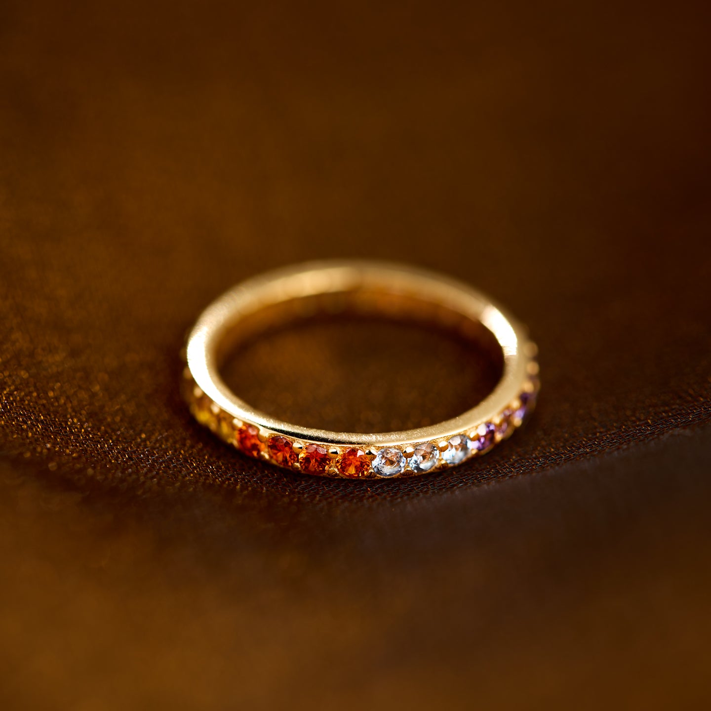 Gold ring with colorful stones on a brown leather surface