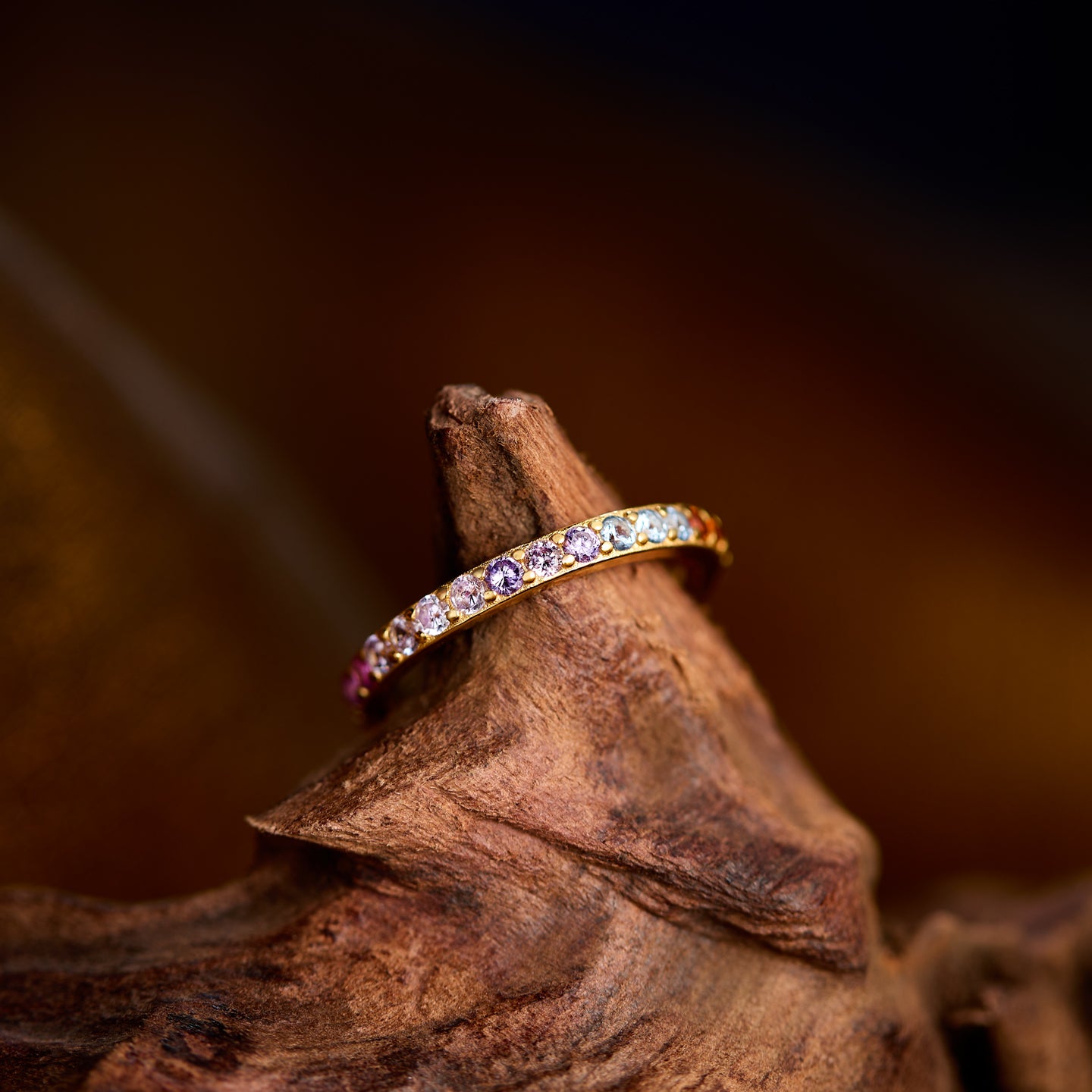 Gold ring with colorful stones on a wooden surface