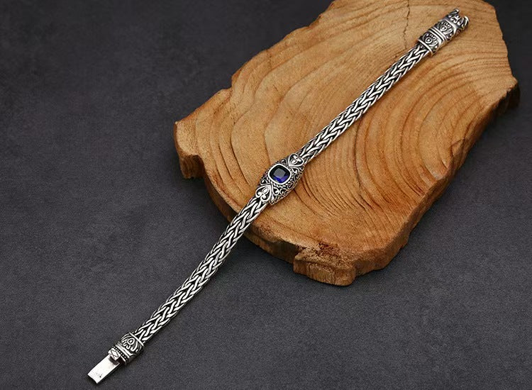 Silver bracelet with a blue gemstone on a wooden block against a dark background