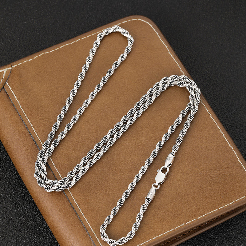 Silver chain necklace on a brown leather surface