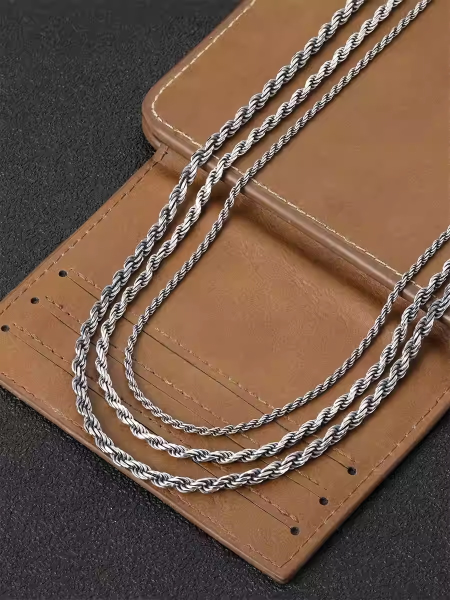 Two silver necklaces on a brown leather surface