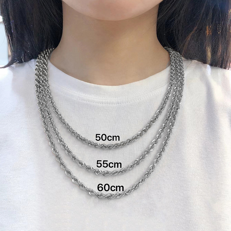 Three silver chain necklaces of different lengths worn on a white shirt.