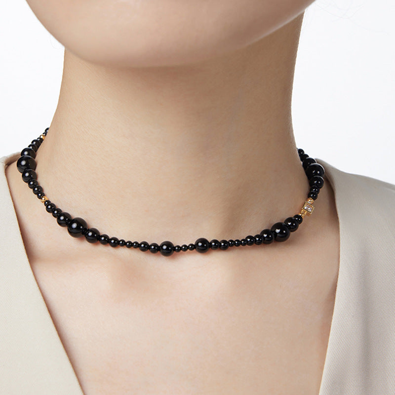 Black beaded necklace on a mannequin with a plain background