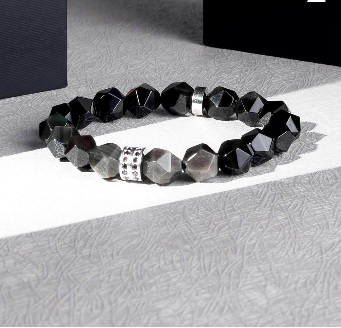Black beaded bracelet with silver accents on a textured surface