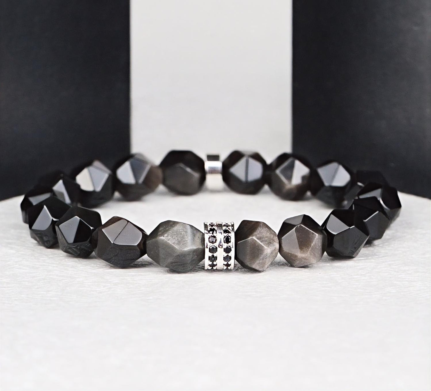 Black beaded bracelet with a silver clasp on a white surface