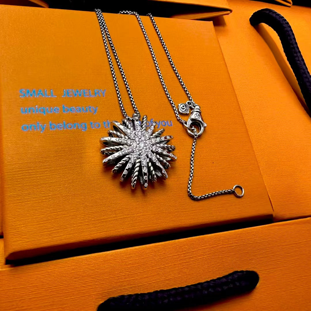 Silver necklace with a sunflower pendant on an orange jewelry box
