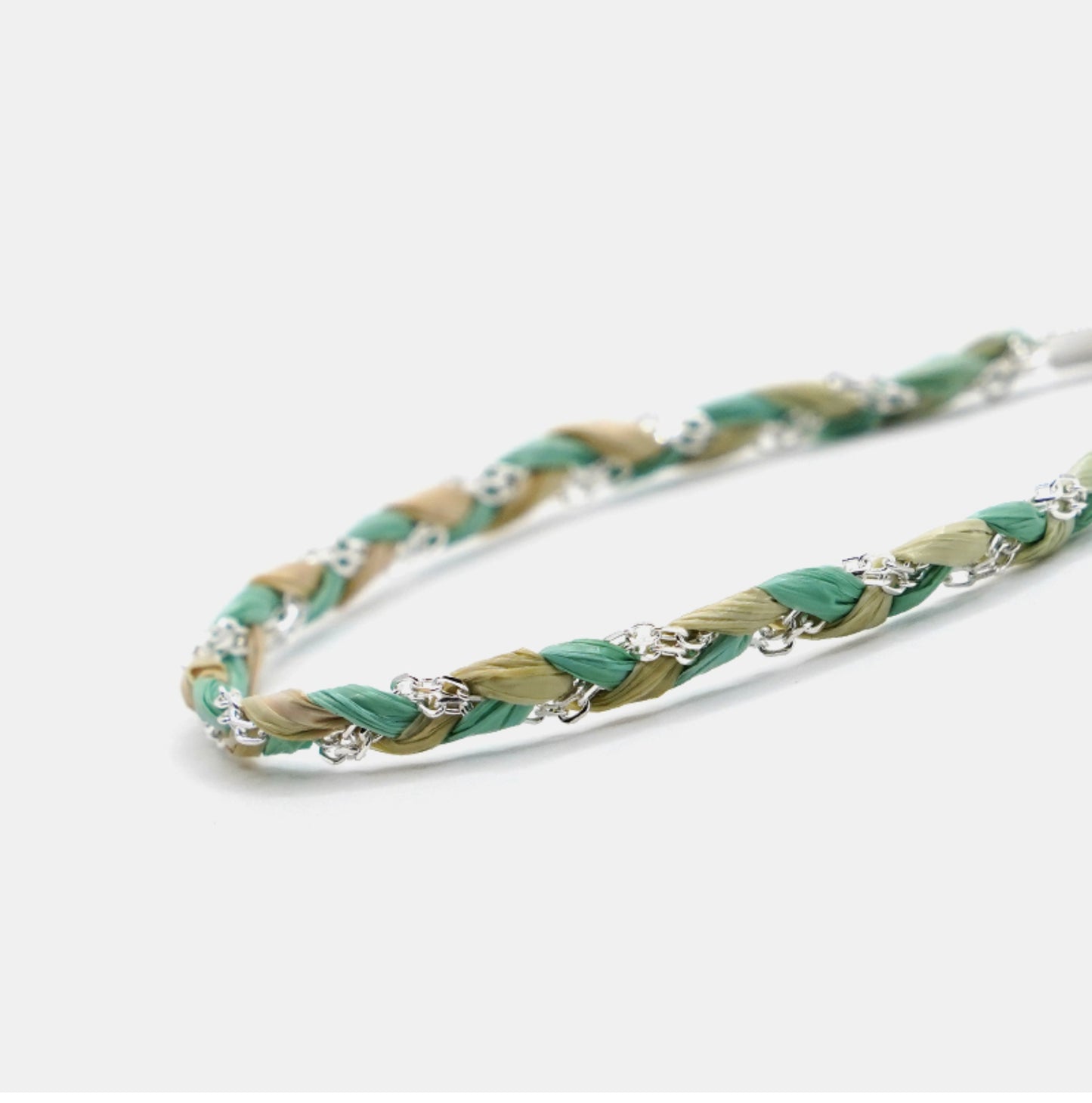 Braided bracelet with green and beige strands on a white background