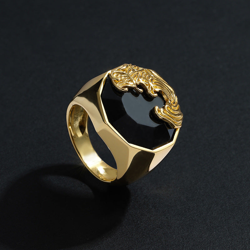 Gold ring with a black stone and dragon design on a dark background