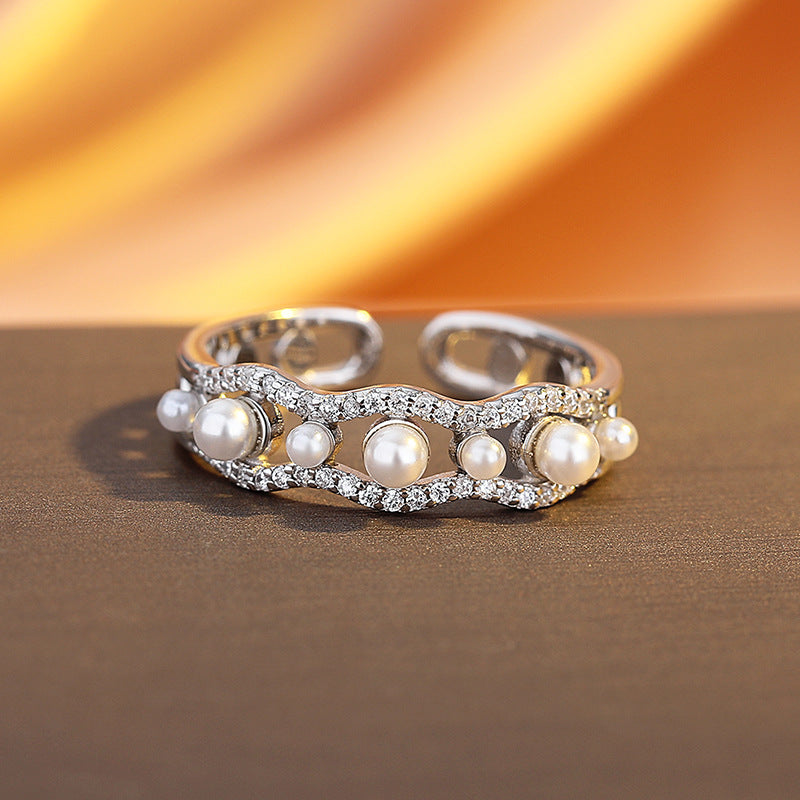 Silver ring with pearls on a brown surface