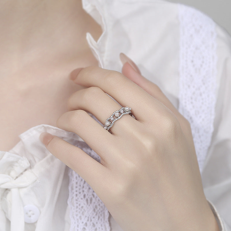 Close-up of a hand wearing a silver ring with gemstones on a white background