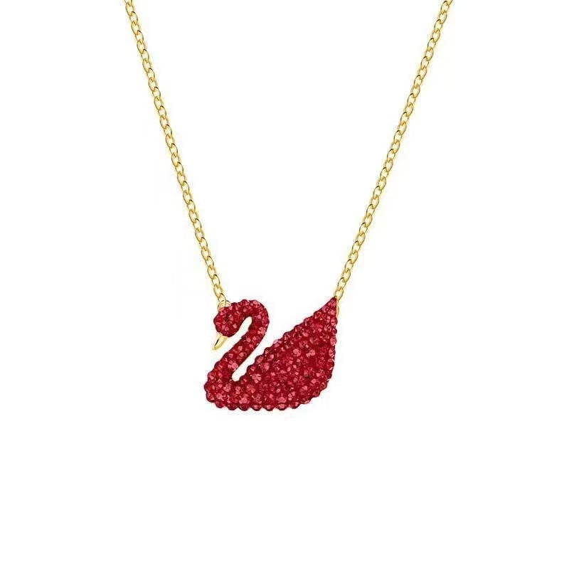 Red swan pendant necklace on a gold chain against a white background