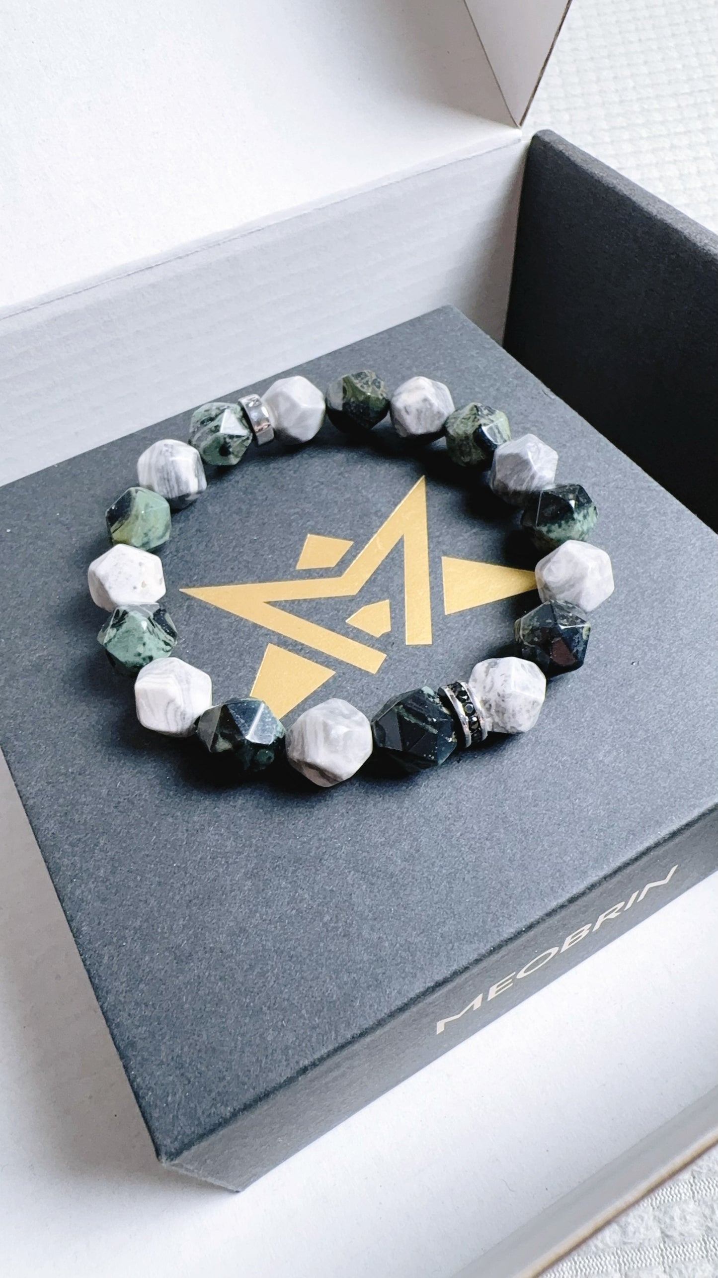 Bracelet with green and white stones on a branded box