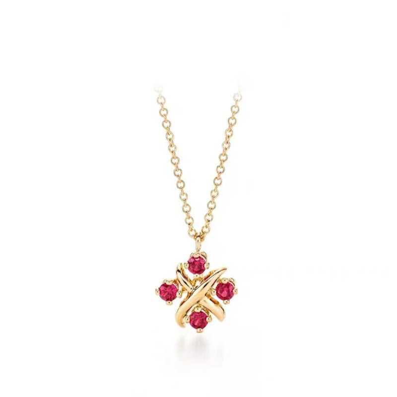 A gold chain necklace with a pendant featuring four small red gemstones and an intertwined gold cross design, set against a plain white background.