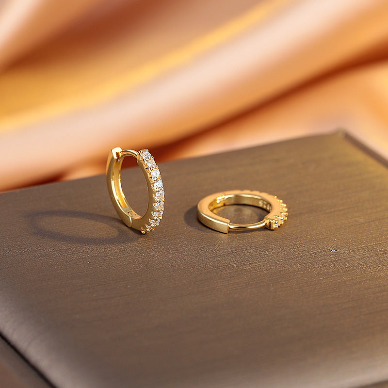 Gold hoop earrings on a soft fabric background
