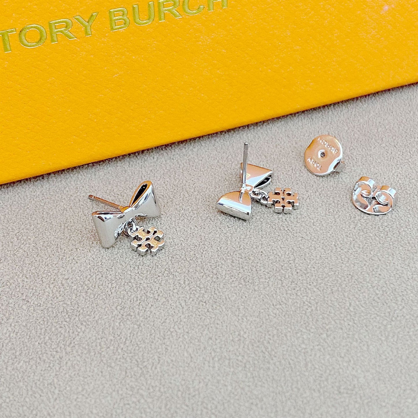 Extreme close-up of one earring showing the bow detailing and polished finish.