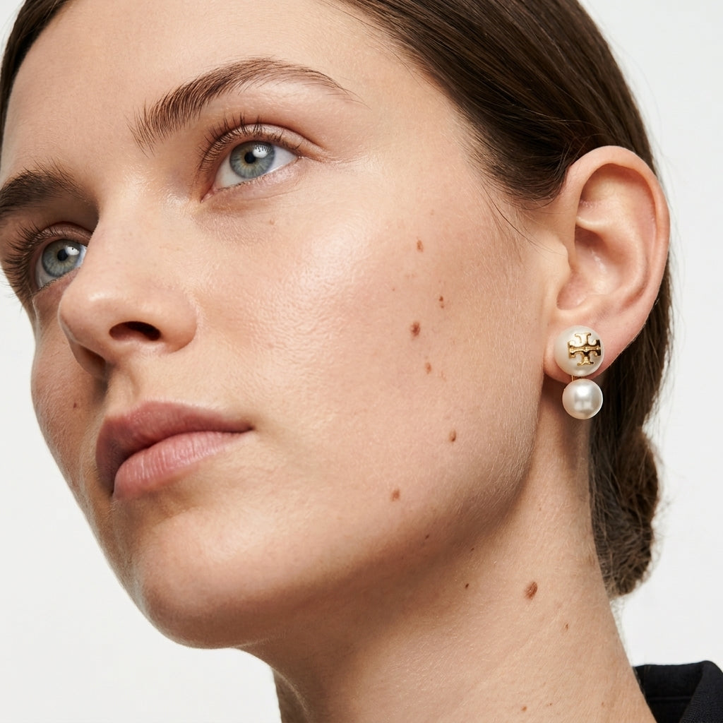 Close-up of a woman wearing a pearl earring with a neutral background
