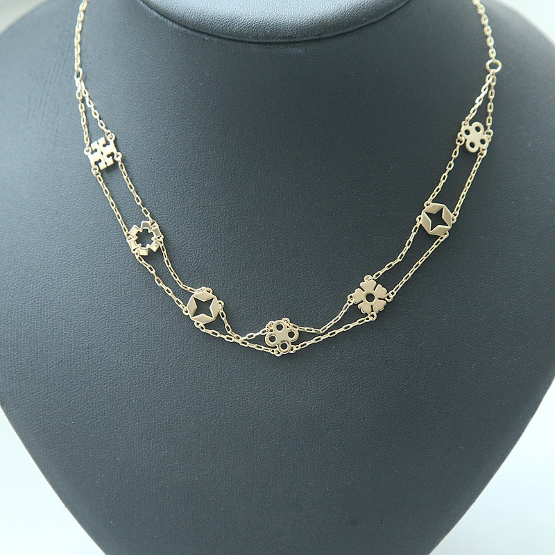 A delicate gold-toned double-strand necklace with small geometric and floral star-shaped links, displayed on a matte black jewelry bust.