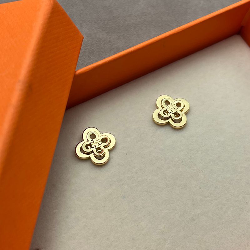 Both earrings displayed face-up on a light, textured background (like linen or soft suede), highlighting the clover shape and engraved detailing.