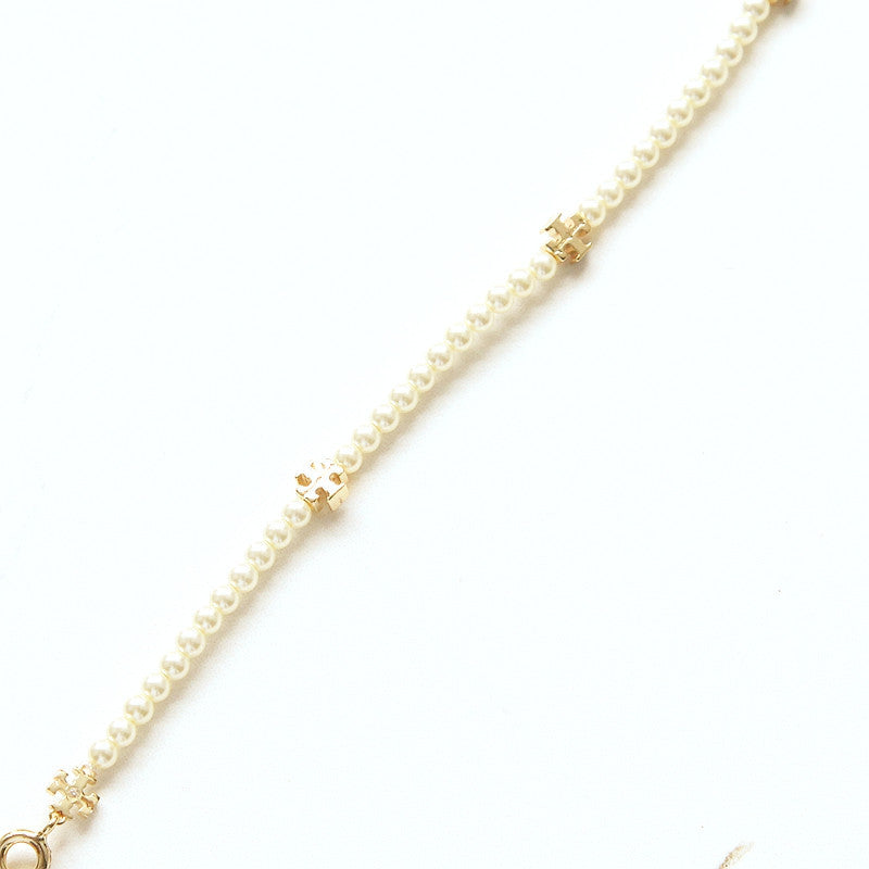 A delicate pearl chain bracelet with small gold-toned decorative links, shown diagonally on a clean white background.