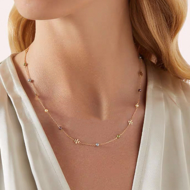 The necklace worn with a crisp white button-down shirt or simple black top, showing how the two charms rest elegantly near the collarbone.