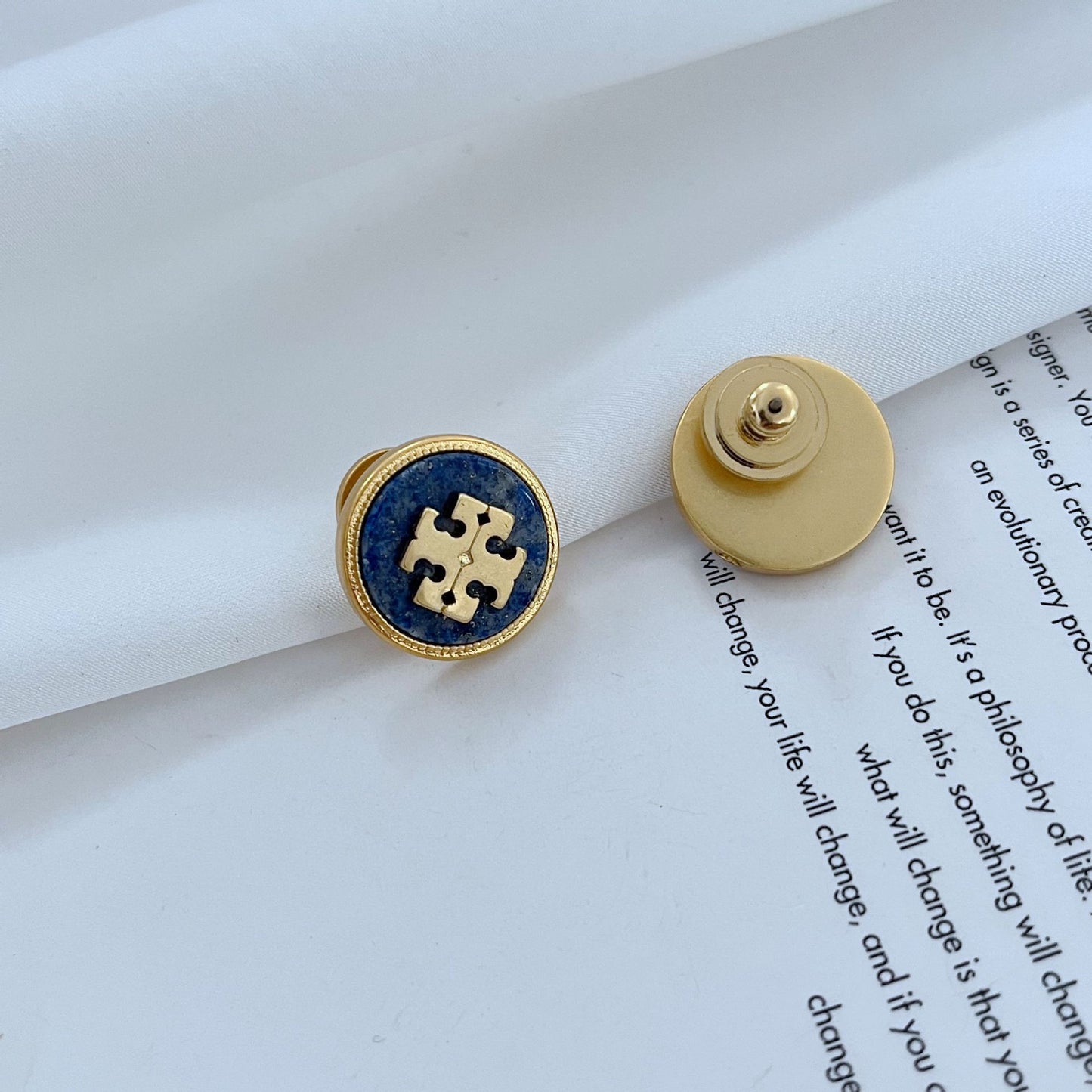 Gold and blue earring on a book page