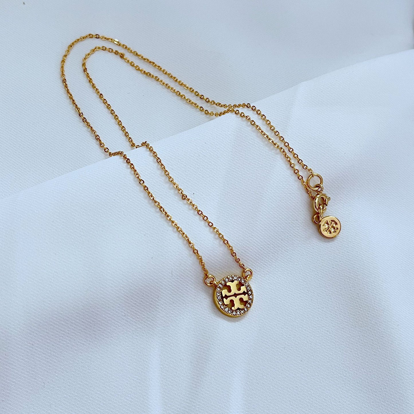 Necklace displayed on a dark, non-reflective surface (black velvet or slate), highlighting the intense sparkle of the crystals against the rich gold plating.