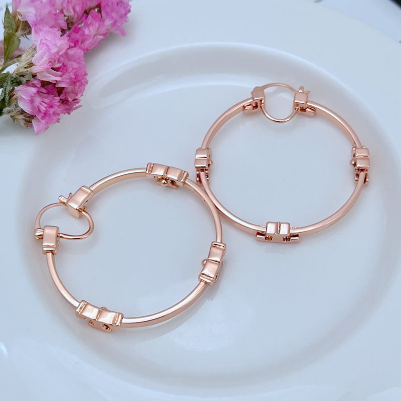 "Lifestyle flat lay composition with the gold Serif T Hoop Earrings arranged on a marble surface beside a minimalist watch and a latte, evoking a chic, modern aesthetic."