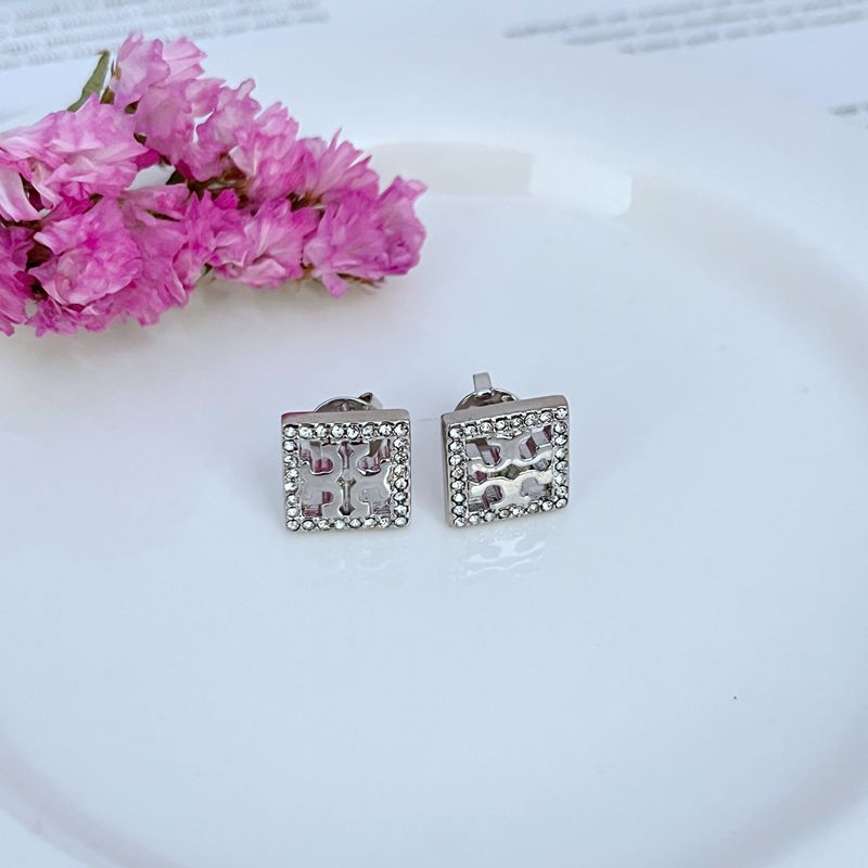 Studs worn on a model, capturing how the square shape and crystals catch light and create a striking focal point on the earlobe.