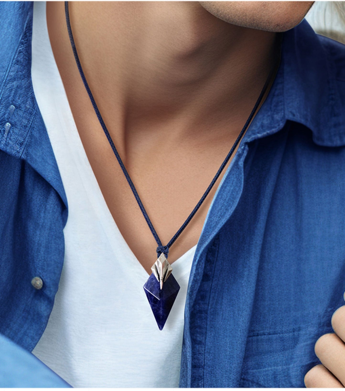 Person wearing a blue shirt with a necklace featuring a silver pendant.