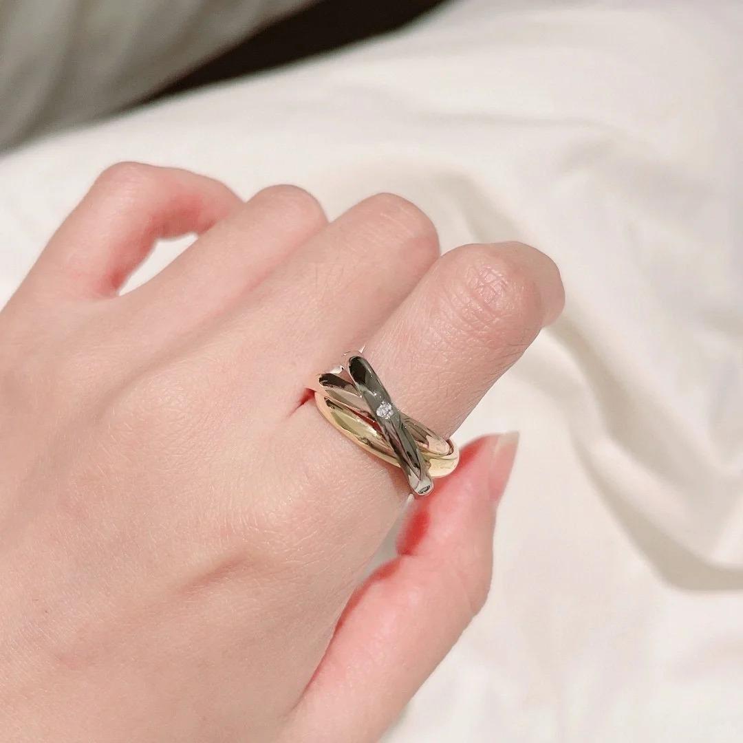 Trinity Tricolor Interlocking Rings Gold ring on a person's finger against a neutral background