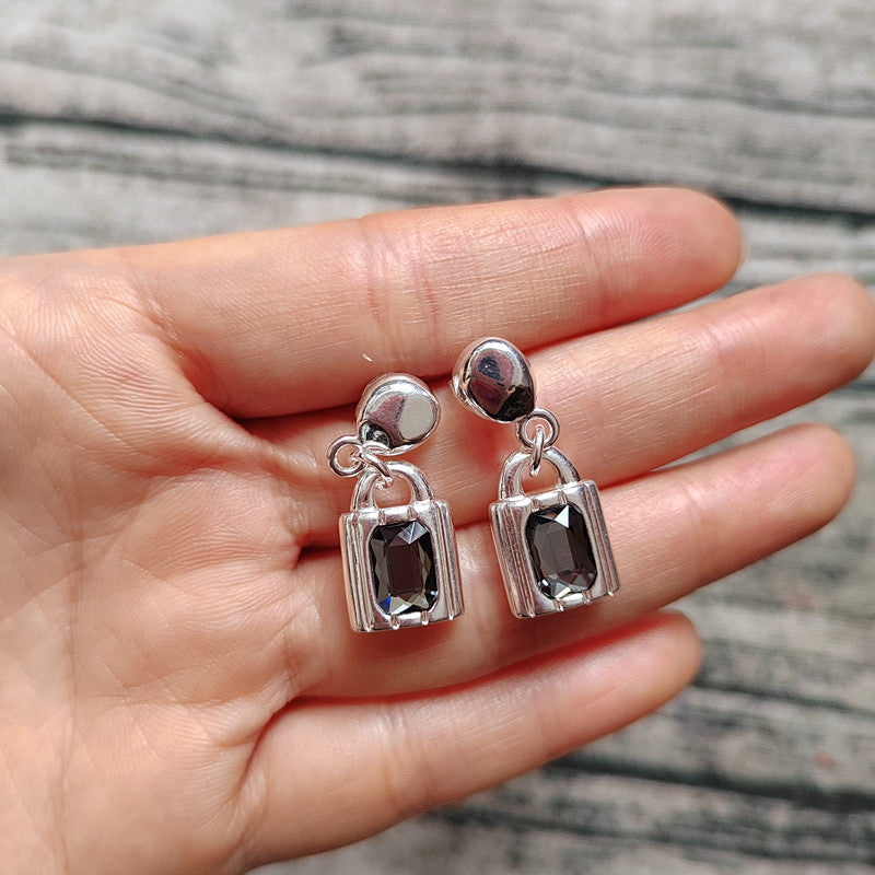 Earrings on neutral background showing padlock charms. Alt: “UNOde50 Padlock-Shaped Drop Earrings – Silver Lock Drops.”