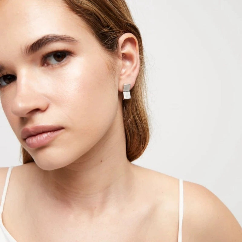 Earrings worn as minimalist statement. Alt: “Modern Geometry: UNOde50 Rectangular Studs.”