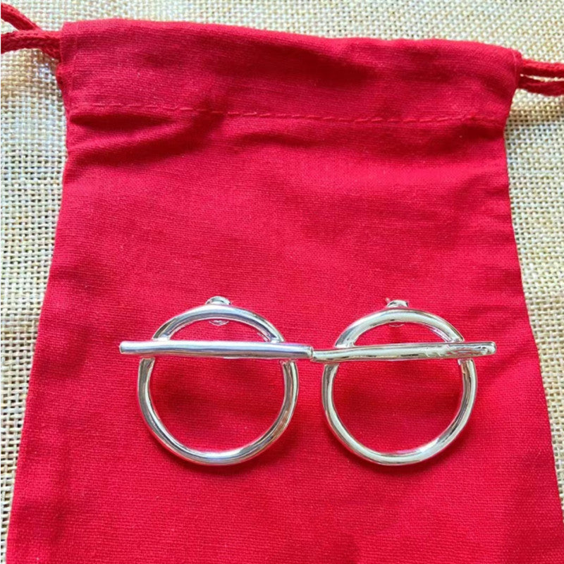 Earrings on neutral background showing switch design. Alt: “UNOde50 Switch On Earrings – Silver Toggle Drops.”