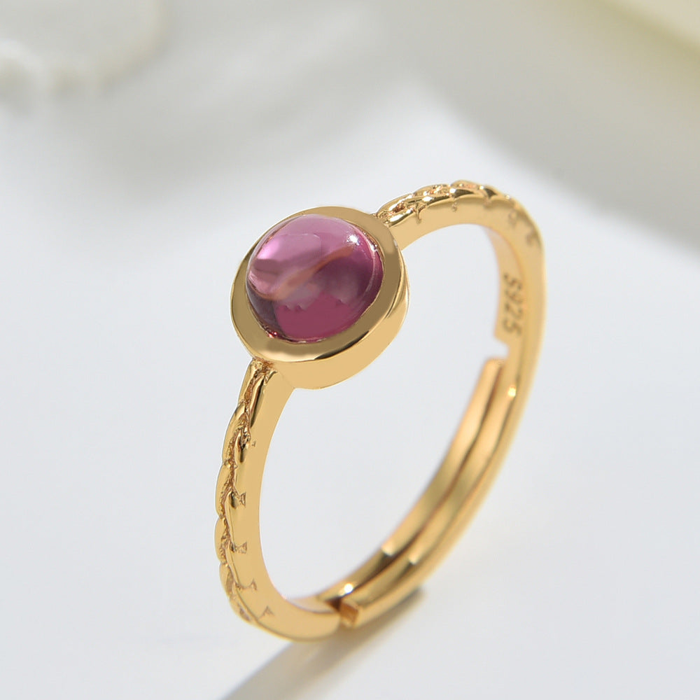 Gold ring with a pink gemstone on a light background