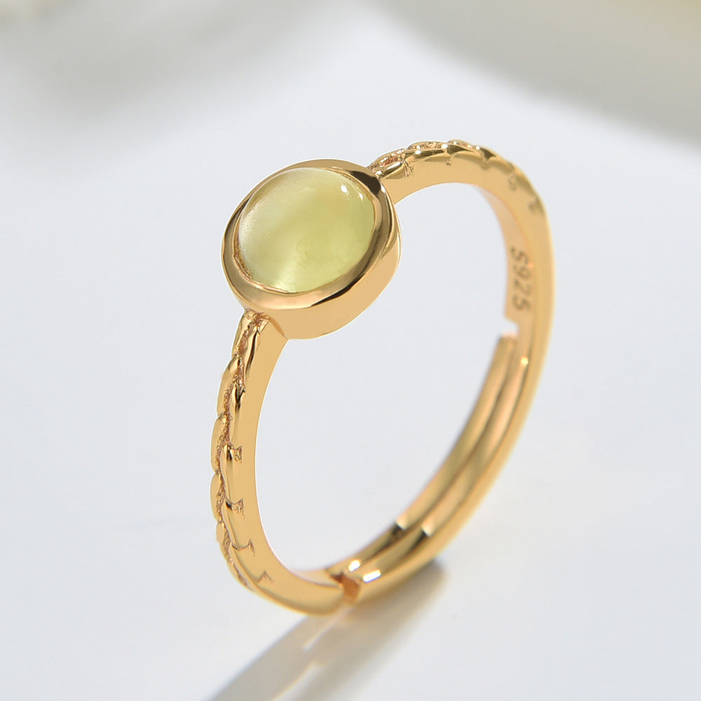 Gold ring with a green gemstone on a light gray background