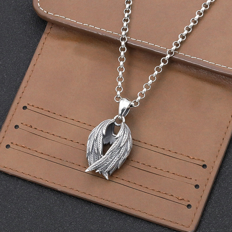 Silver necklace with a leaf pendant on a brown leather surface