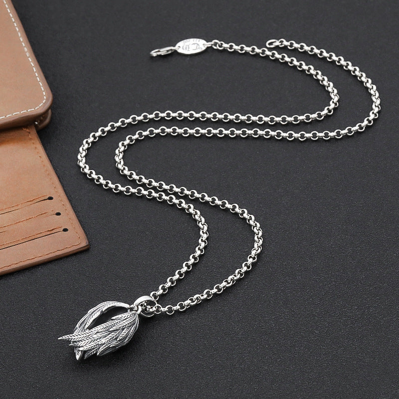 Silver chain necklace with a leaf pendant on a dark surface