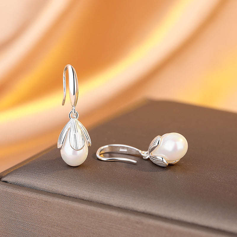Pearl earrings with silver hooks on a soft fabric background