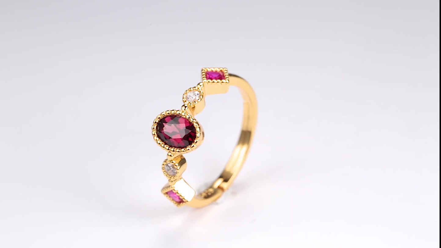 Gold ring with red gemstones on a light gray background