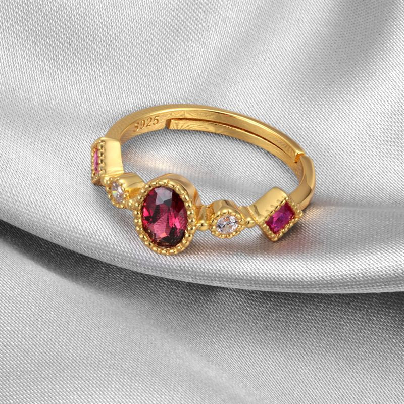 Gold ring with red gemstone and small diamonds on a gray fabric background