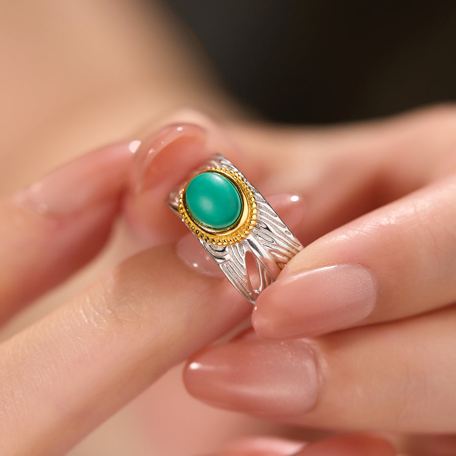 Close-up of a hand wearing a silver and gold ring with a turquoise stone.