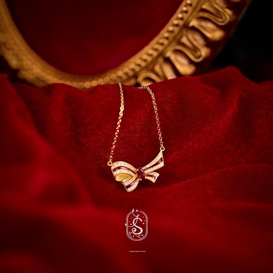 Gold necklace with a bow-shaped pendant on a red fabric background
