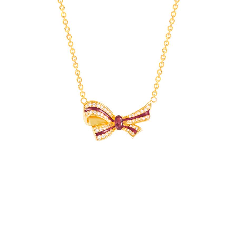 Gold bow-shaped necklace with a red gemstone on a white background
