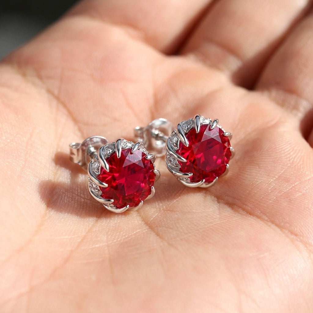 Red gemstone earrings held in a hand