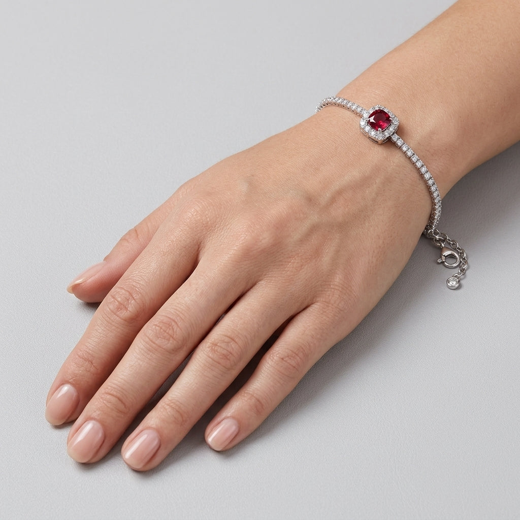 Top-down hand view of a model wearing an elegant cushion-cut ruby halo tennis bracelet resting on a smooth backdrop.