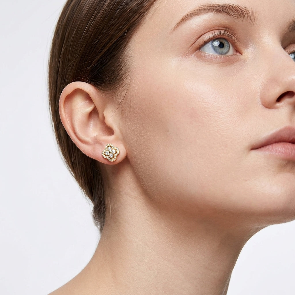 Model wearing gold round cut moissanite four-leaf clover cluster halo studs in a daylight portrait.