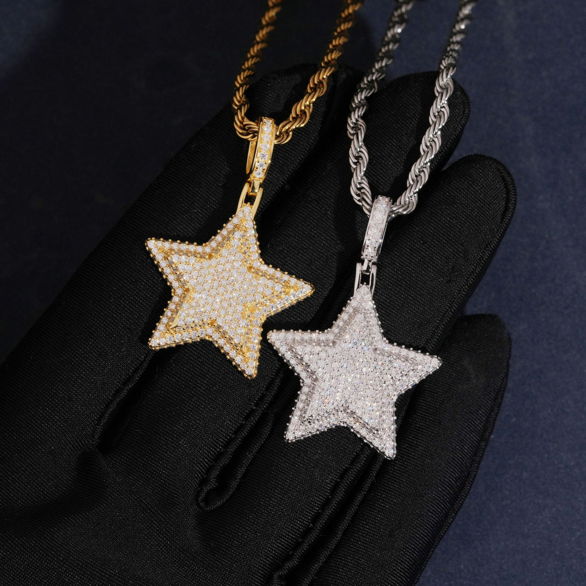 Hand wearing black glove holding gold and silver S925 moissanite 3D star hip hop pendants on rope chains