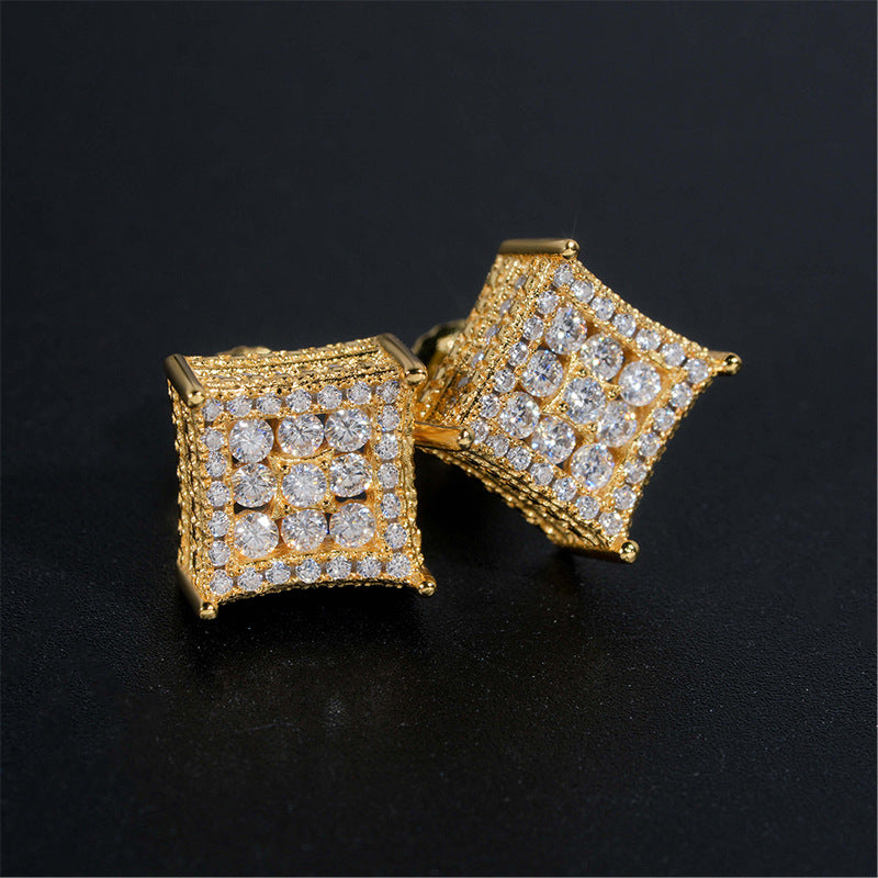 Pair of yellow gold iced out curved kite cluster moissanite stud earrings on dark surface