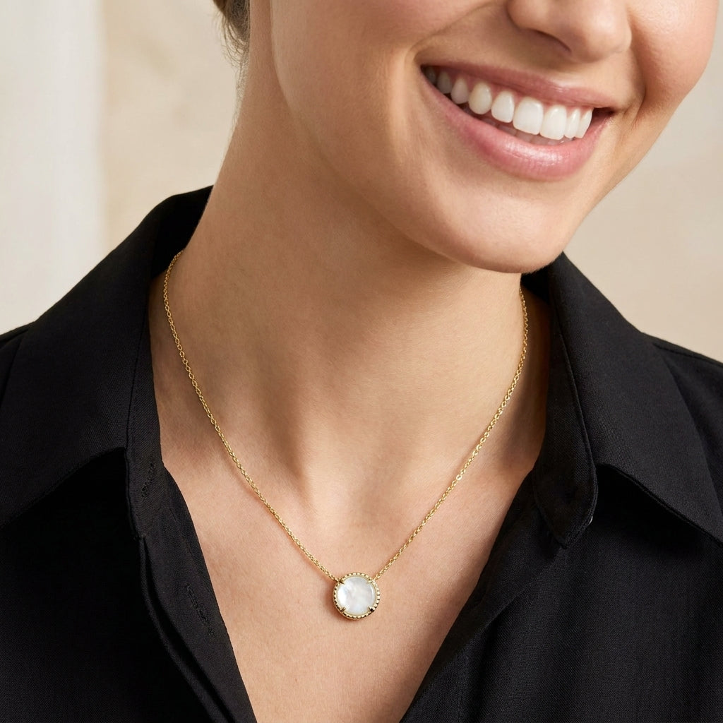 Close-up of a model in a black v-neck shirt wearing the Kendra Scott gold volleyball pendant necklace.