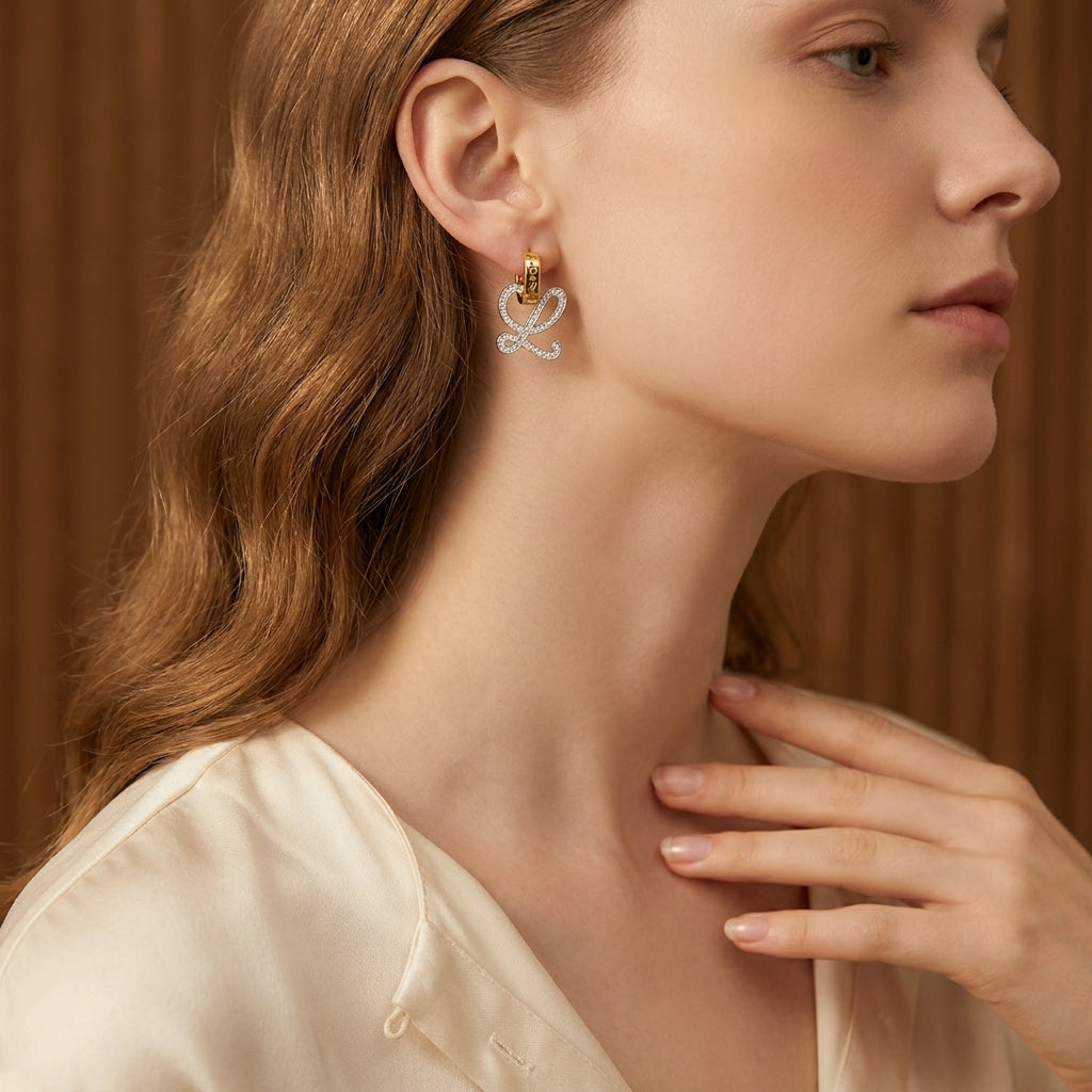 Model touches hair wearing Loewe Anagram L Earrings, capturing the signature logo glint in motion